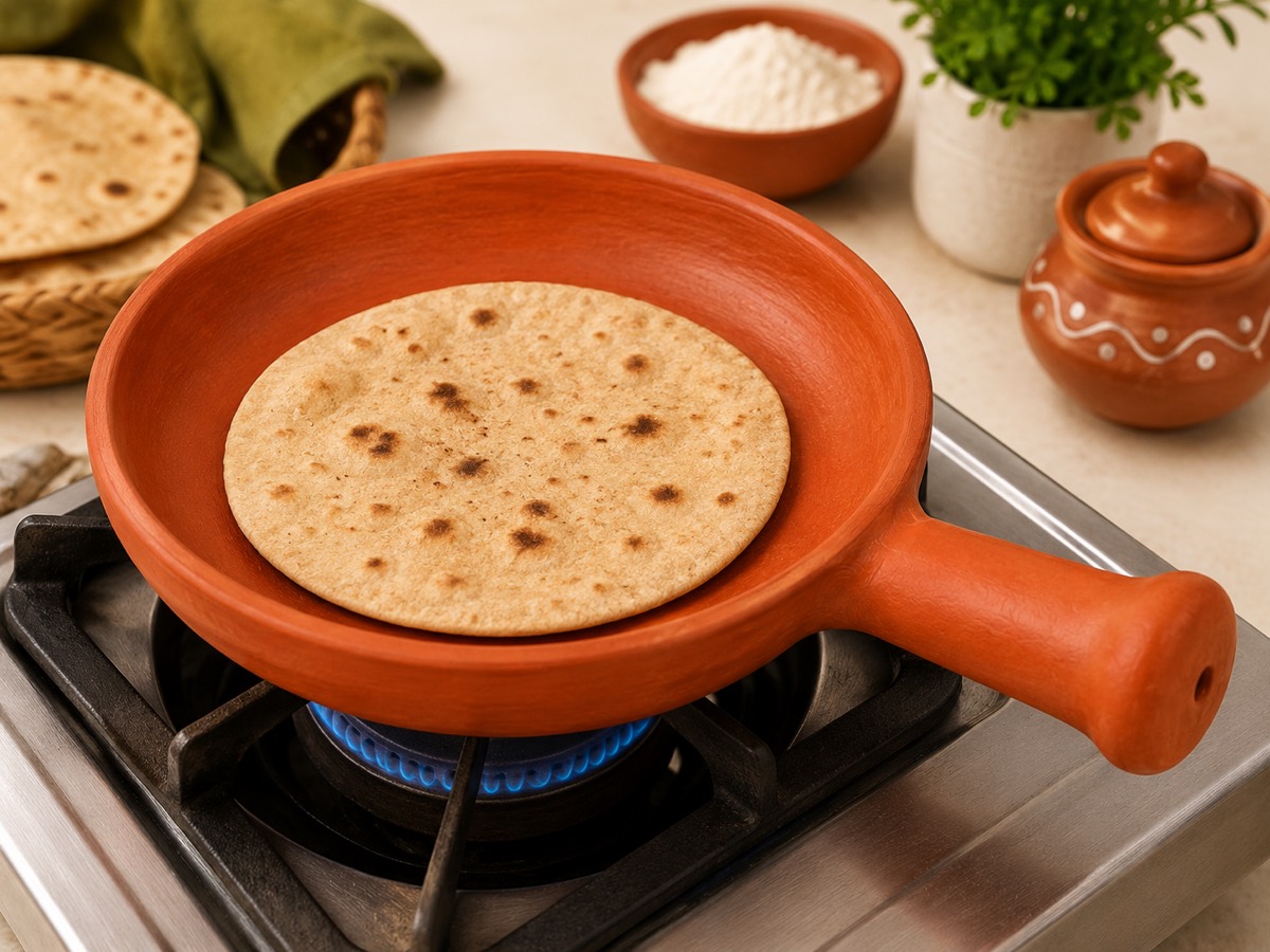 Terracotta tawa with handle cooking a roti on a gas stove
